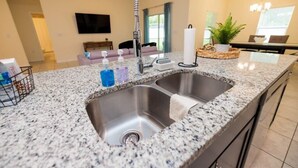 Eine Küche mit Granit Arbeitsplatten, Spüle aus Edelstahl und einem modernen Wasserhahn.