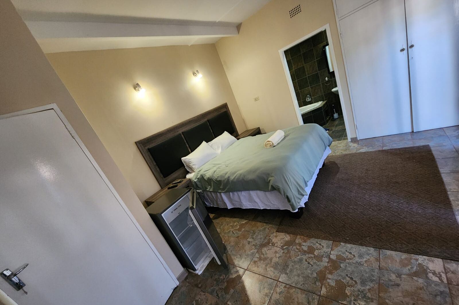 A bedroom with a bed, bedside table, and a wardrobe.