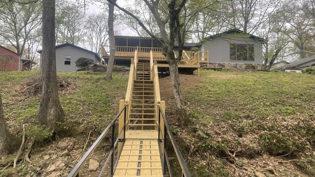 A wooden bridge leading to a house with a deck.