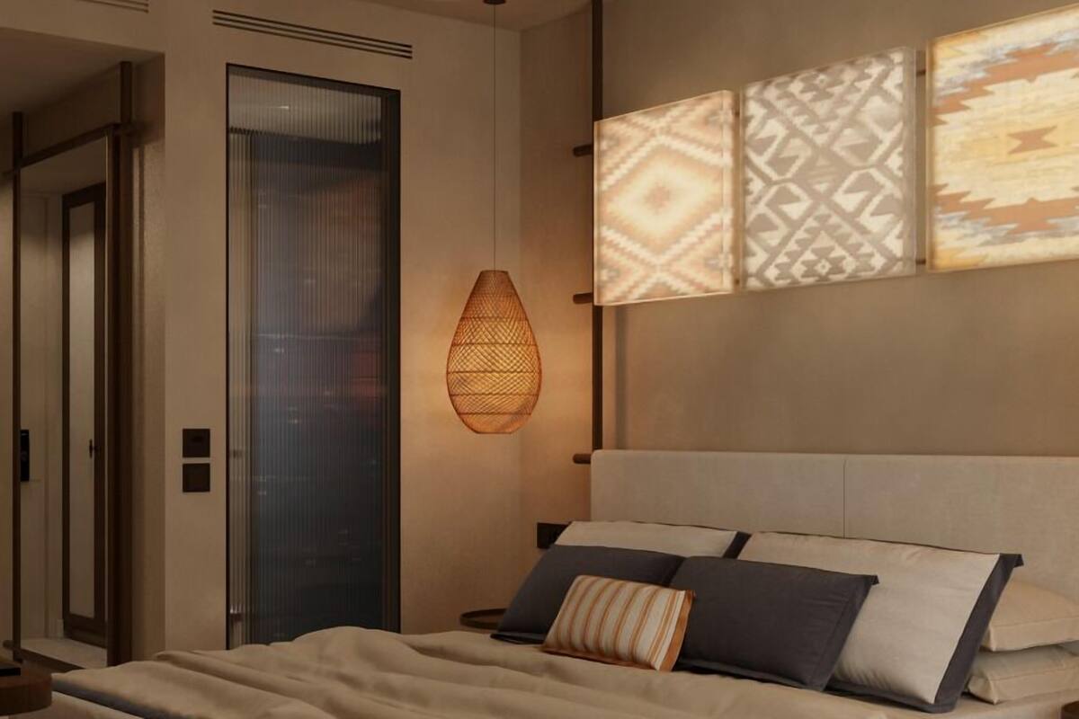 A modern bedroom with a large bed, a hanging light fixture, and patterned wall art.