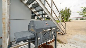 Un barbecue fixé à un bâtiment, avec un escalier métallique permettant d’y accéder.