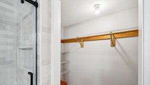 Un dressing avec des murs carrelés de carreaux blancs, un banc en bois et des étagères en métal.