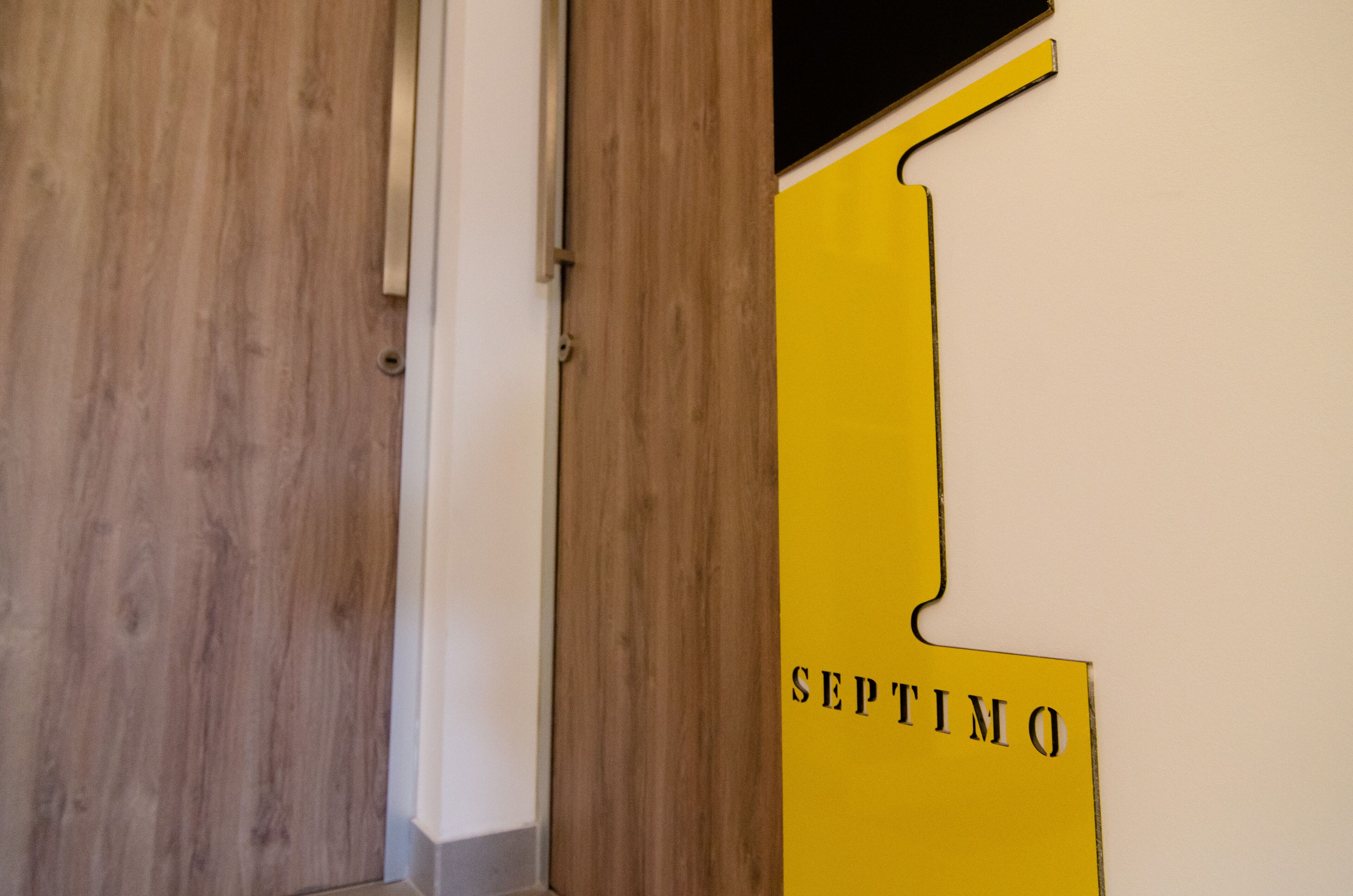 A wooden door and a yellow wall with the text "SEPTIMO".