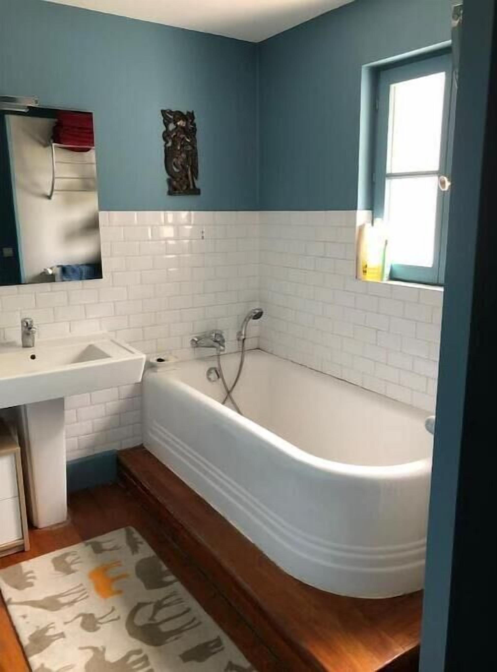 A bathroom with a white bathtub, a sink, and a mirror.