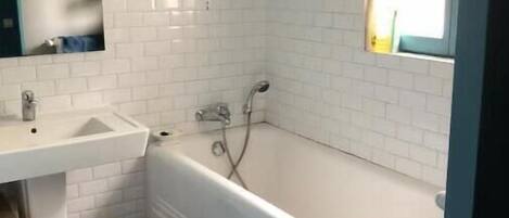 A bathroom with a white bathtub, a sink, and a mirror.
