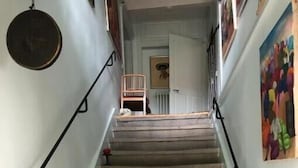 A staircase with a handrail, a small table, and a chair at the top.