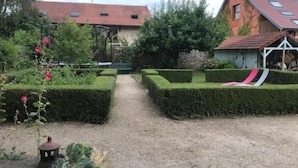 A garden with a gravel path, neatly trimmed hedges, and a small statue.