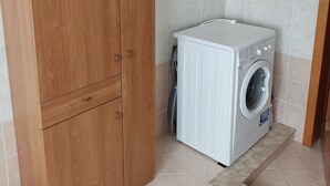 A laundry room with a wooden wardrobe and a white washing machine.