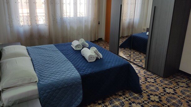 A hotel room with a bed, a smaller bed or sofa, and a mirror.