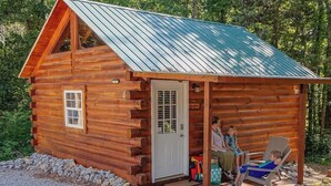 A log cabin with a porch, a door, and a window. - Romantic Log Cabin w/ King Bed & Free Parking (Columbia)