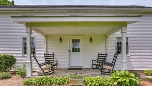 A white house with a porch, two chairs, and a potted plant. - Historic Farmhouse in Layton w/ Deck! (Layton)