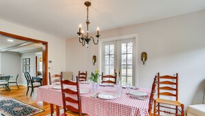 A dining area with a checkered tablecloth, wooden chairs, and a chandelier. - Historic Farmhouse in Layton w/ Deck! (Layton)