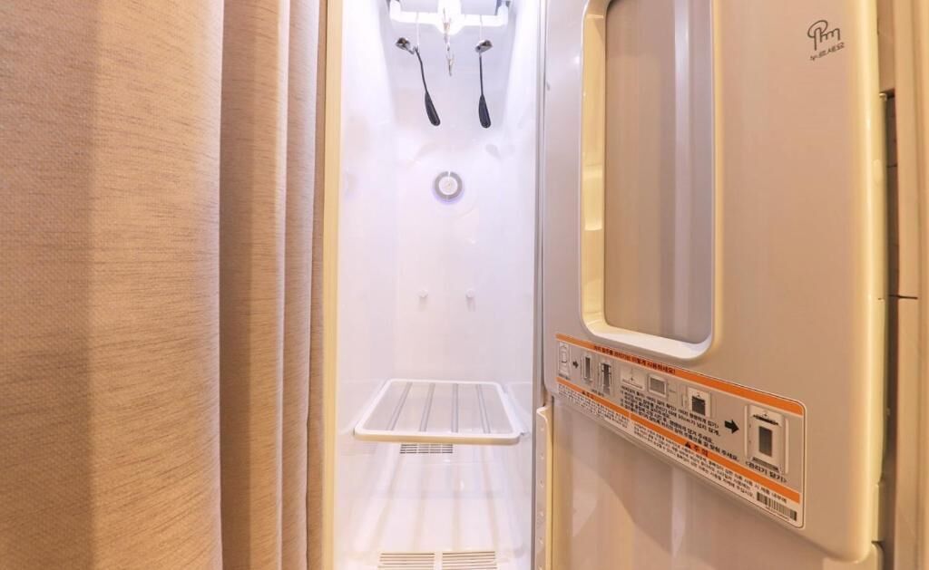 Un baño moderno y compacto con lavamanos integrado, espejo y zona de ducha.
