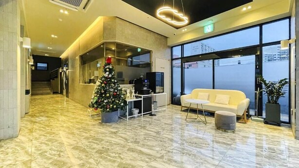A modern lobby with a Christmas tree, a sofa, and a large window.