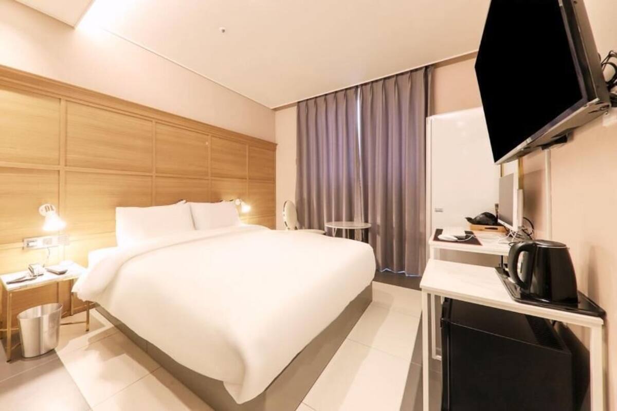 Une chambre d’hôtel avec un grand lit, un bureau avec un ordinateur, une télévision et une machine à café.