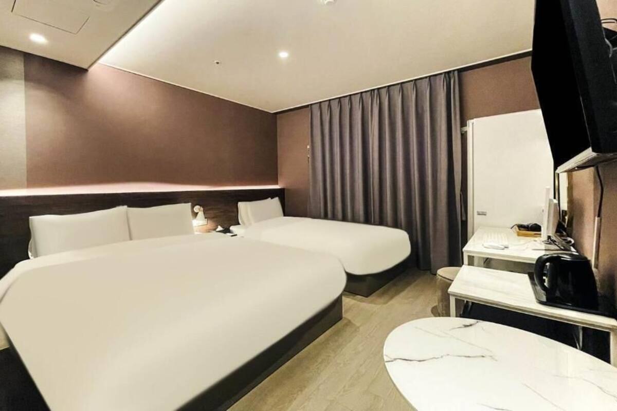 Une chambre d’hôtel avec deux lits, un bureau avec une chaise, un téléviseur à écran plat et une petite table avec une machine à café.