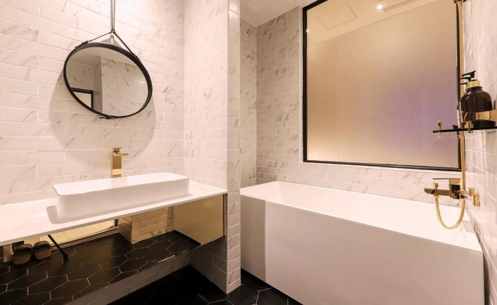 A modern bathroom with a white sink, a large mirror, and a bathtub.