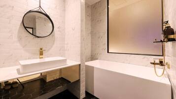 A modern bathroom with a white sink, a large mirror, and a bathtub.