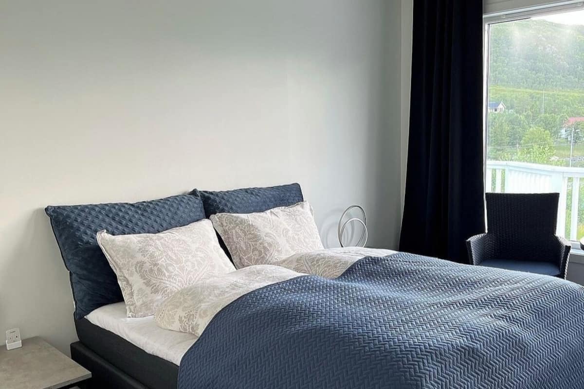 Une chambre moderne avec un lit, une petite table, une chaise et une vue sur la verdure à l’extérieur.