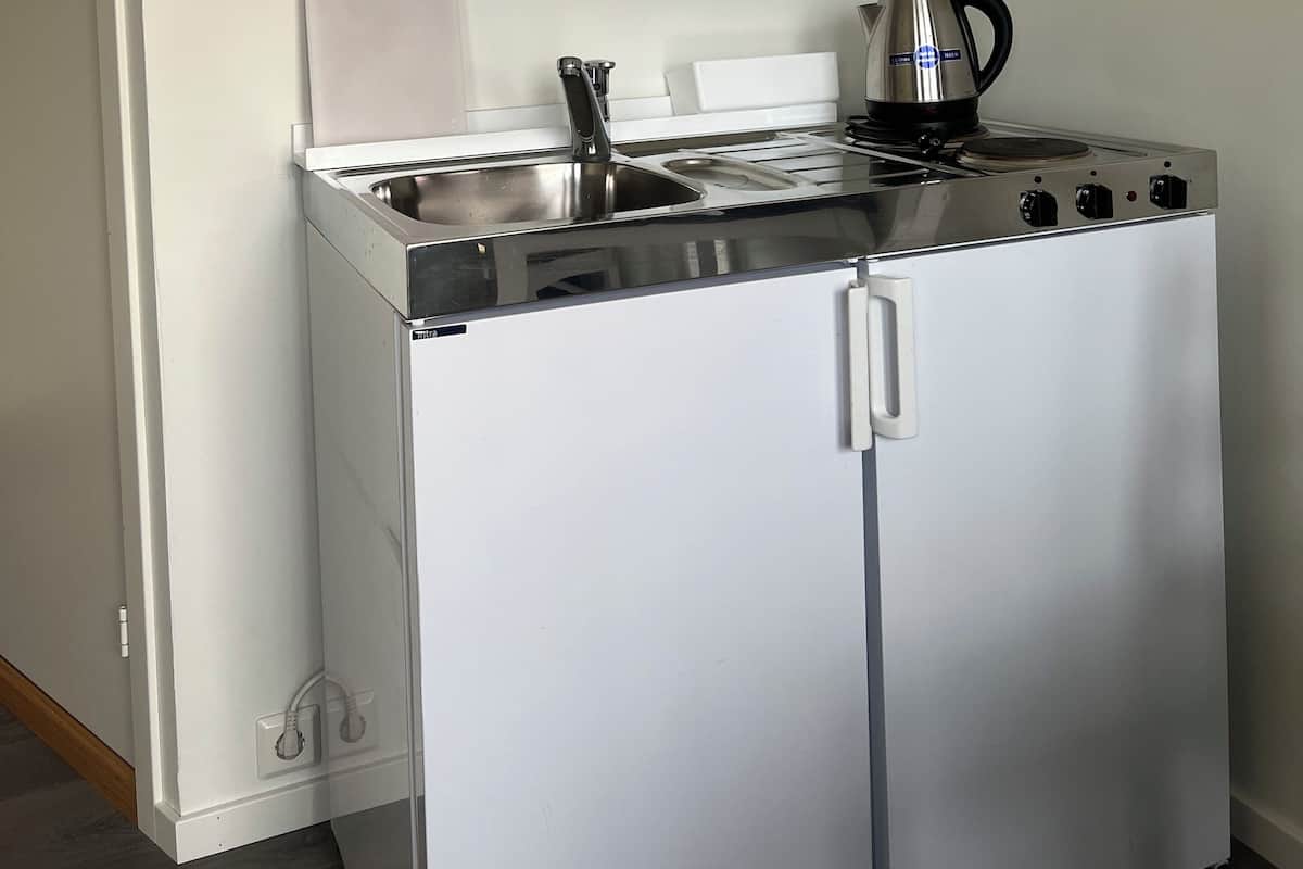 Une petite cuisine équipée avec une cuisinière blanche, un évier et un meuble de rangement.