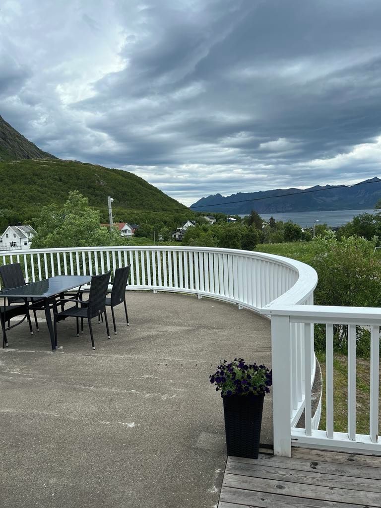 Una terraza con una mesa y sillas, con vista a un paisaje montañoso.