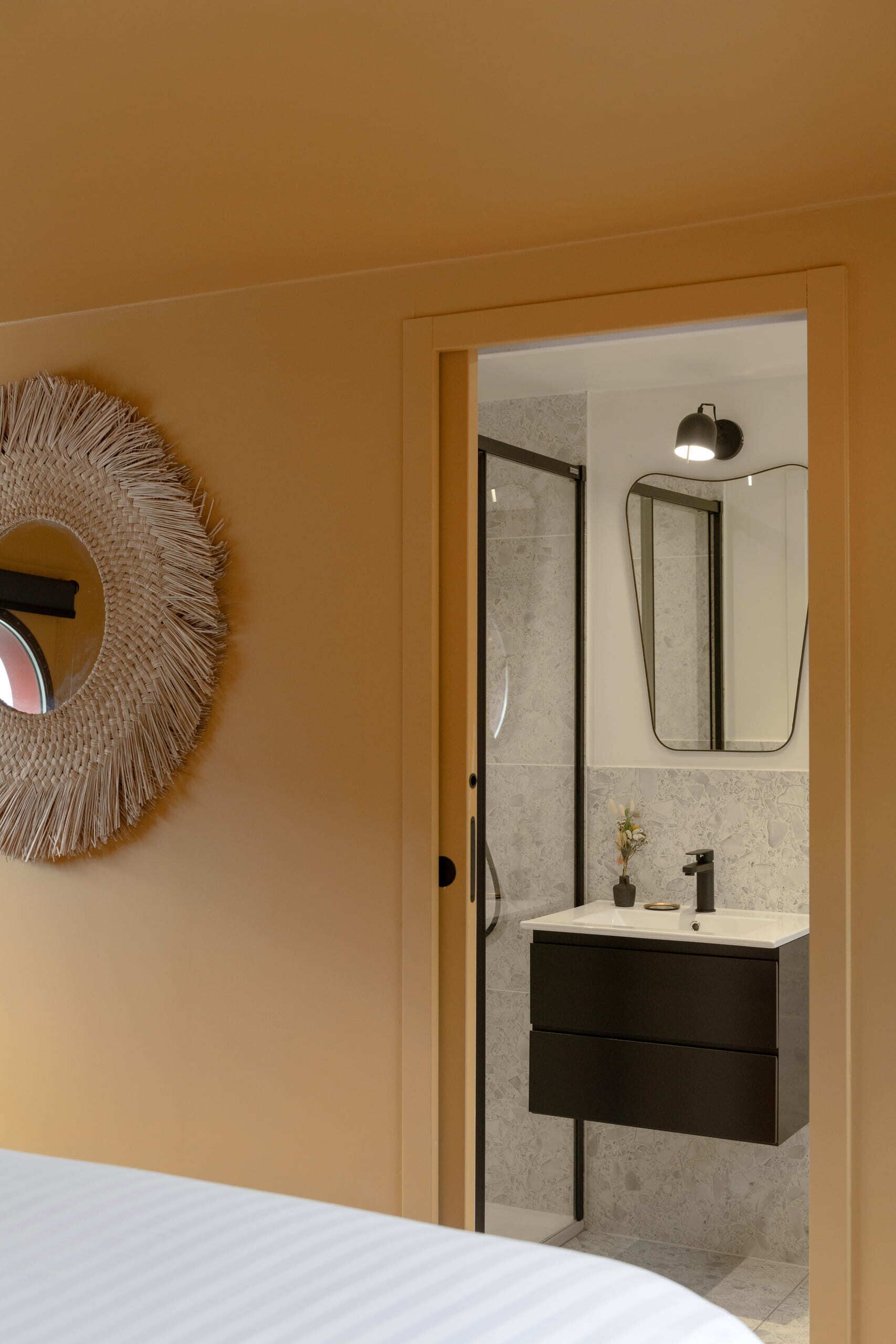 Un baño moderno con un espejo redondo, un adorno circular en la pared y un lavabo blanco.