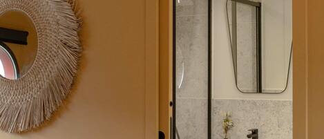 Un baño moderno con un espejo redondo, un adorno circular en la pared y un lavabo blanco.