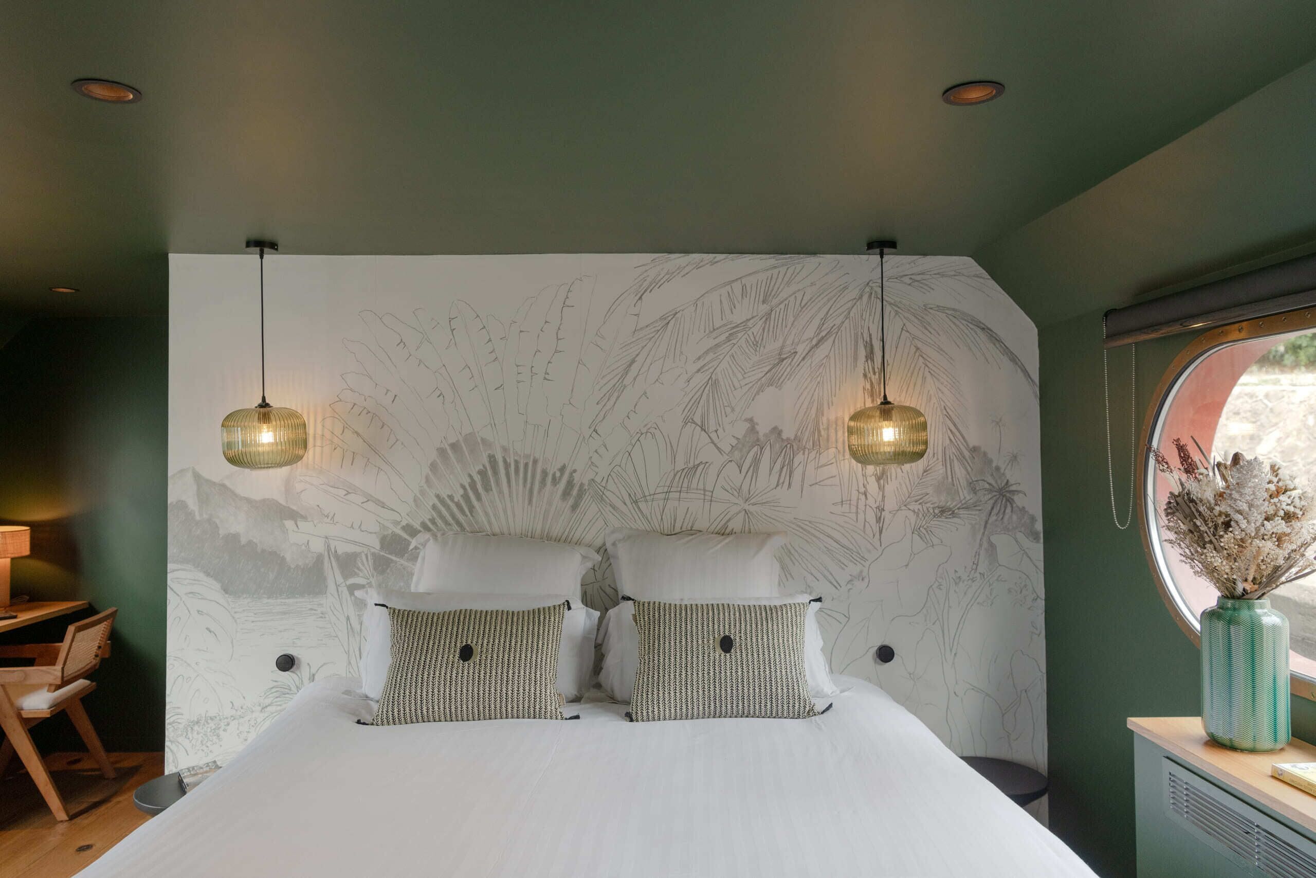 Een slaapkamer met een groot bed, twee nachtkastjes, een bureau en een raam met uitzicht.