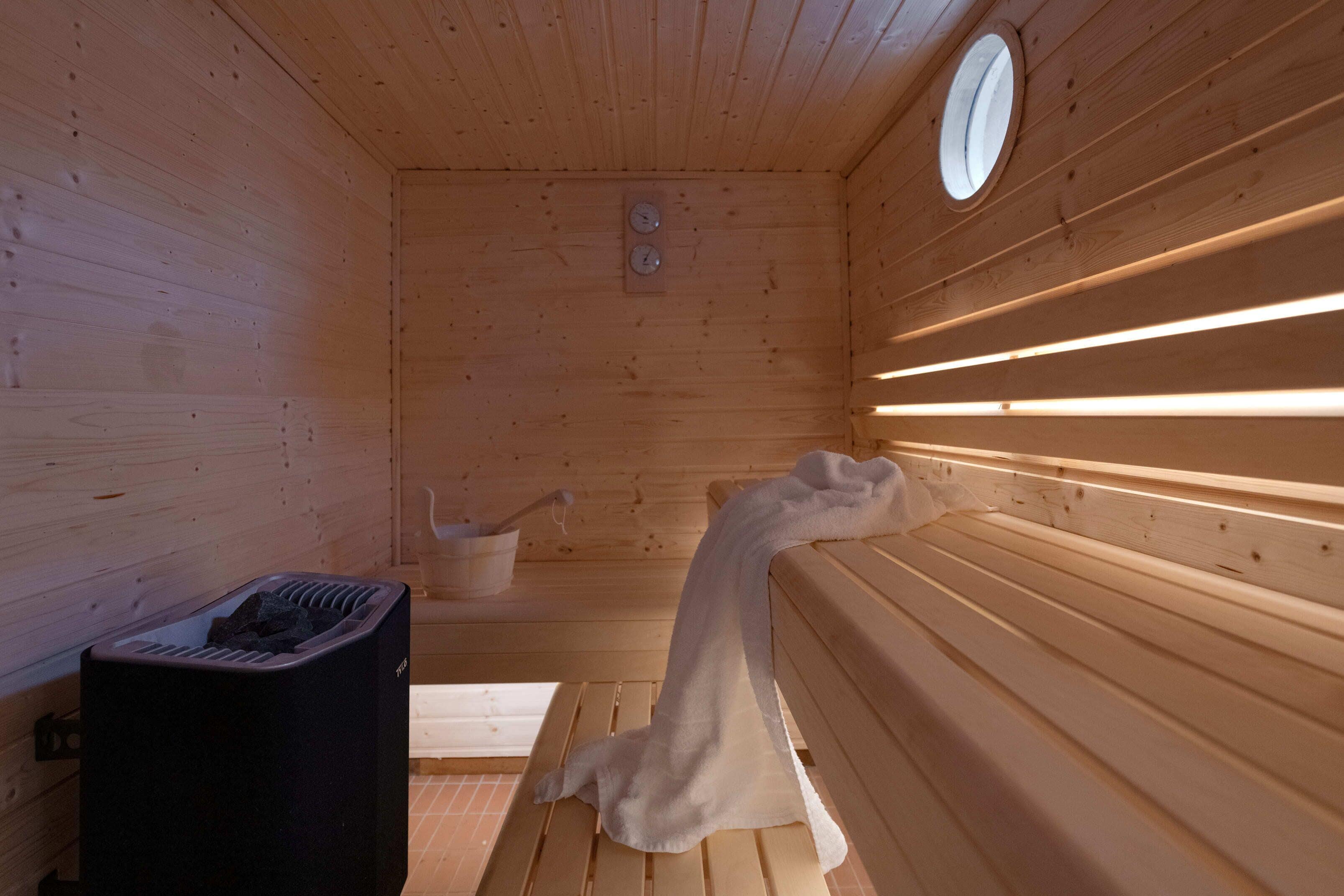 A sauna with wooden walls, benches, and a towel draped over one bench.