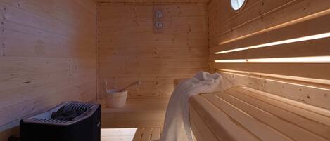 A sauna with wooden walls, benches, and a towel draped over one bench.