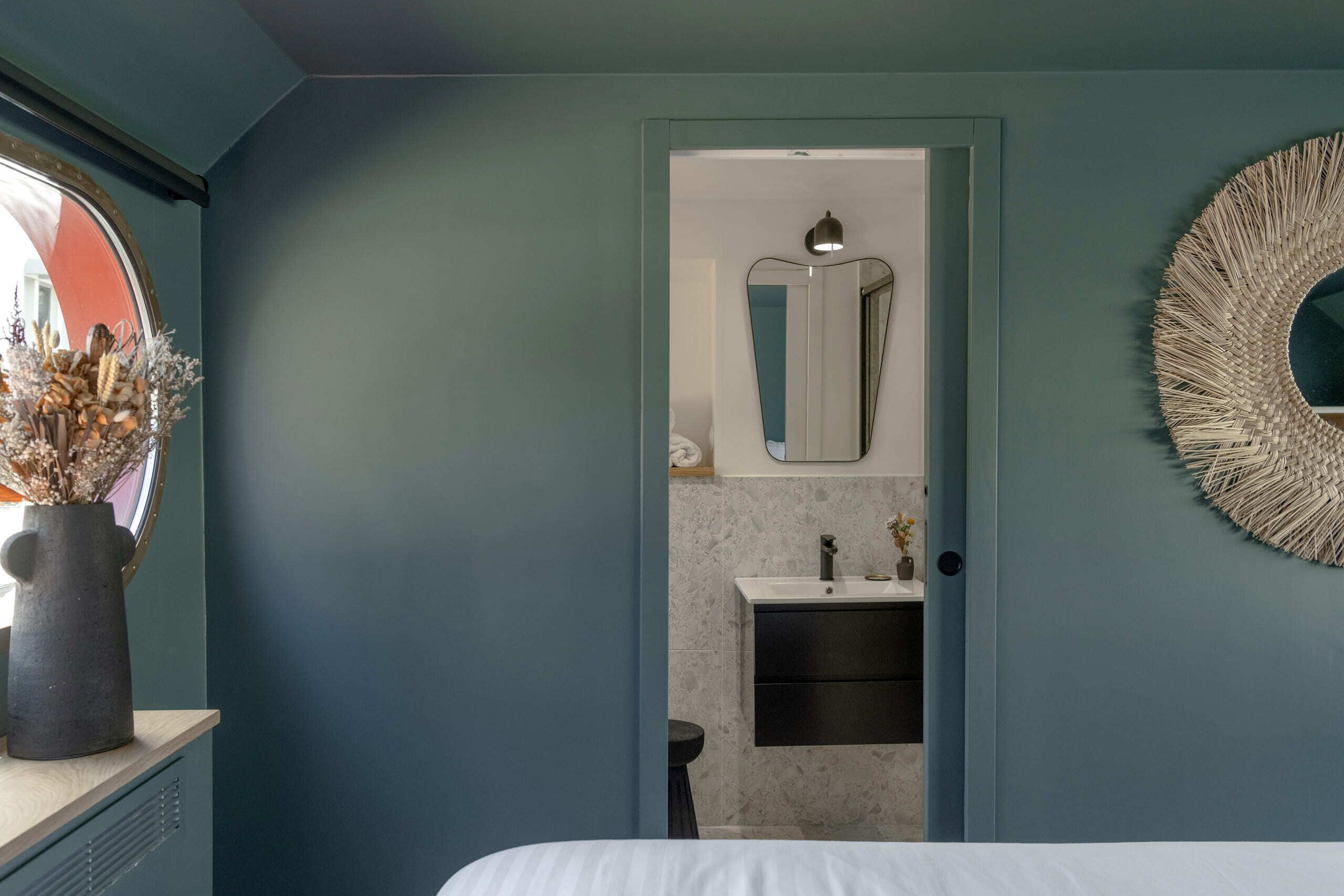 Ein Schlafzimmer mit einem Bett, einem Schminktisch, einem Spiegel und einer Tür zu einem Badezimmer.