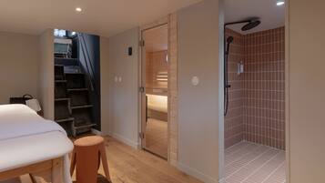 A bedroom with a bed, a wooden stool, a wardrobe, and a shower area with tiled walls.