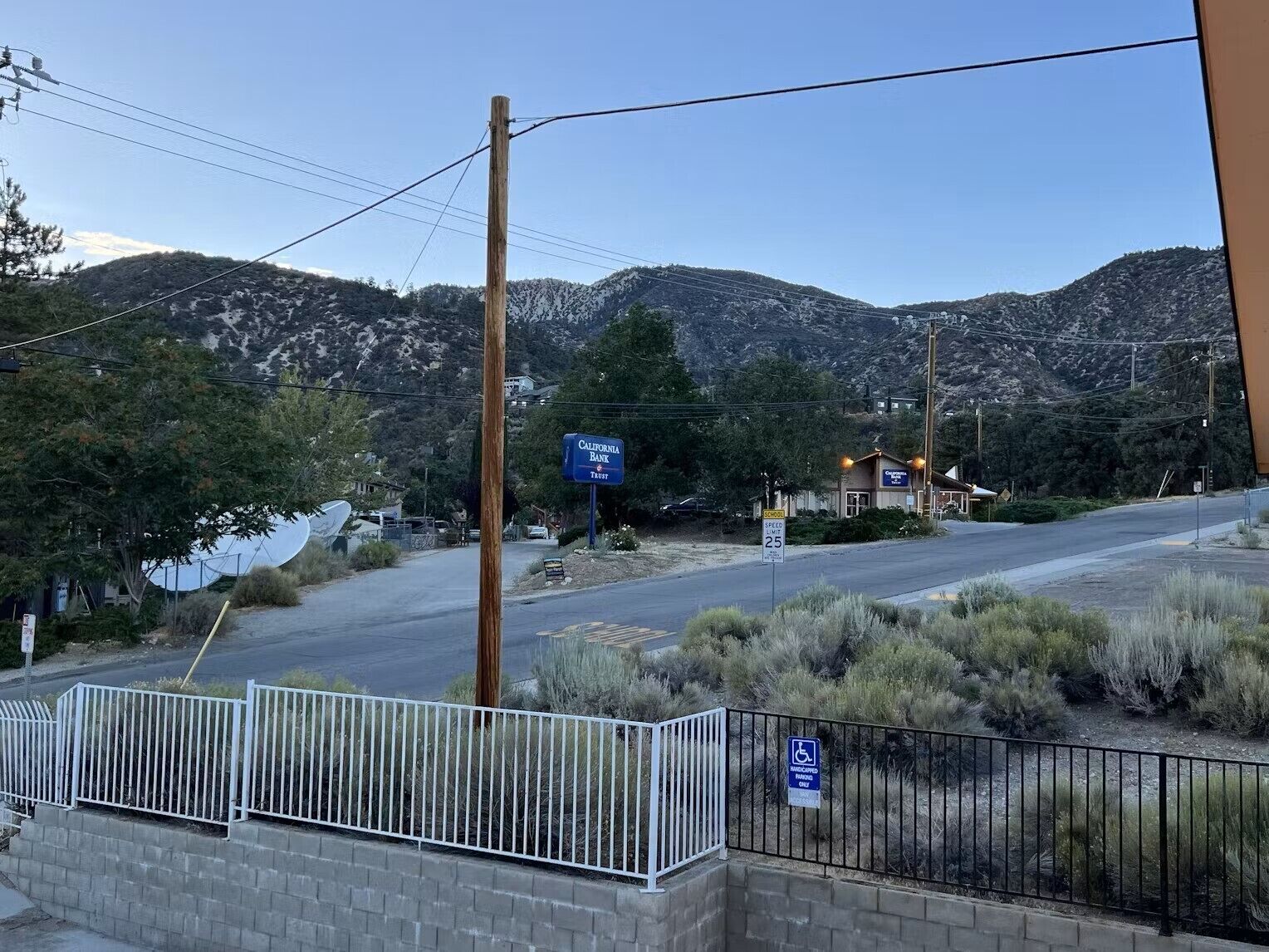 A road with a speed limit sign, a bank sign, and a handicapped parking sign.