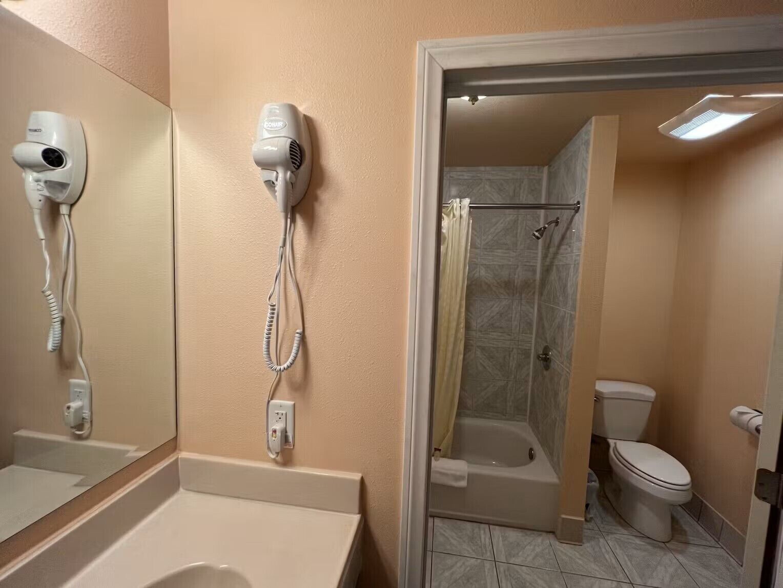 Ein Badezimmer mit Föhn, Badewanne, Toilette und Duschbereich.