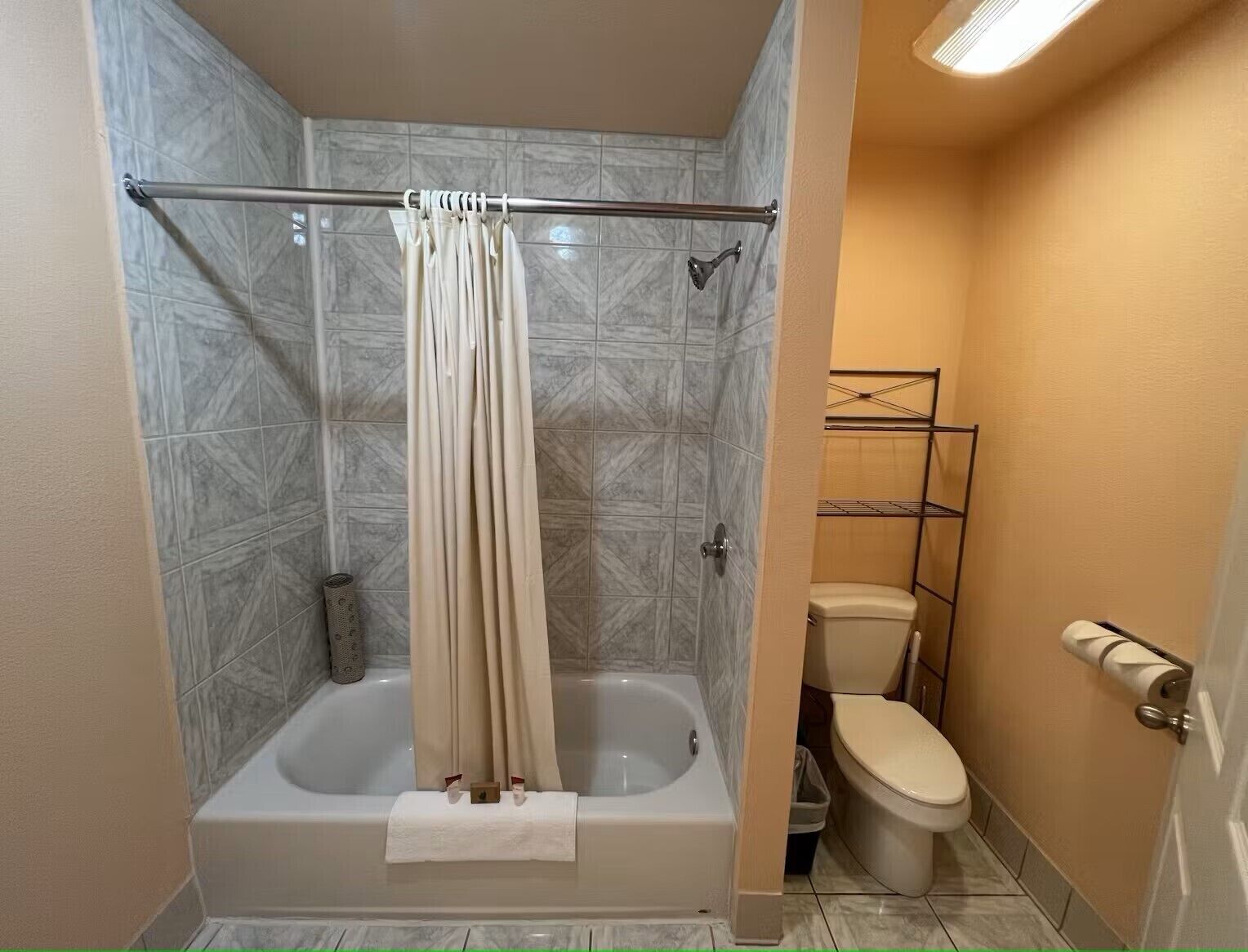 Een badkamer met een bad, toilet en douchegordijn.