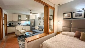Un espacio habitable compacto con kitchenette, un sofá, una cama y un espejo grande.