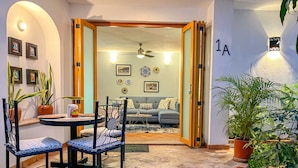 Una sala de estar acogedora con una mesa de comedor, sillas y un sofá. Hay plantas en macetas y cuadros en las paredes.