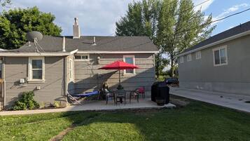 A residential backyard with a patio, a barbecue grill, and a satellite dish.