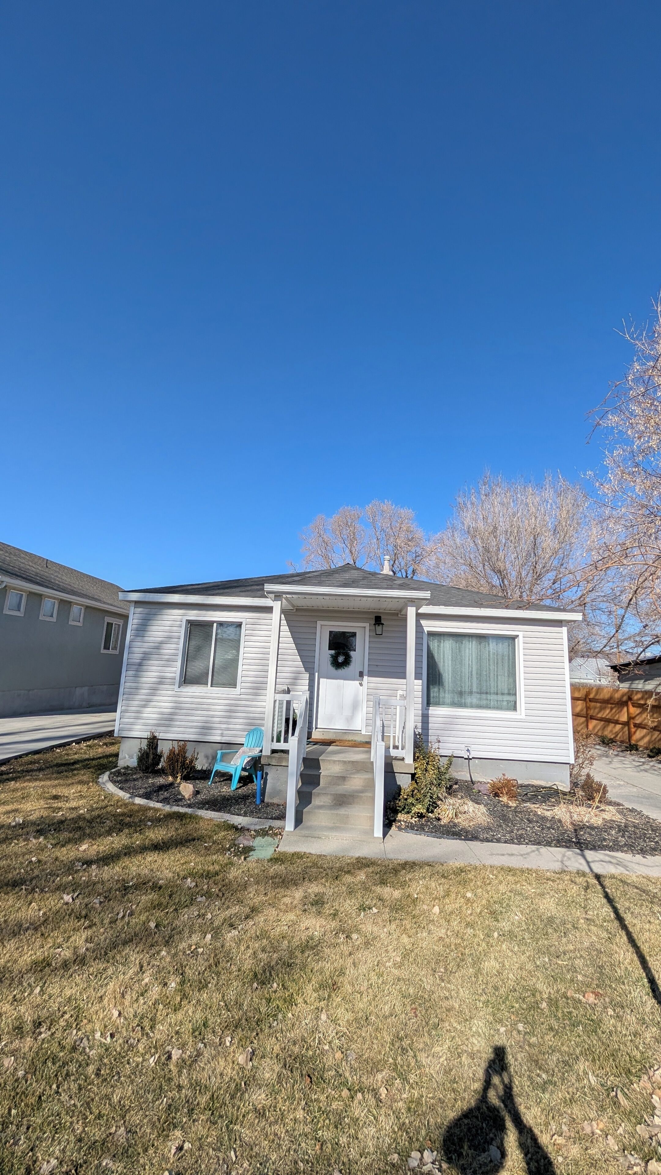 A single-story house with a front porch, a small front yard, and a clear blue sky.