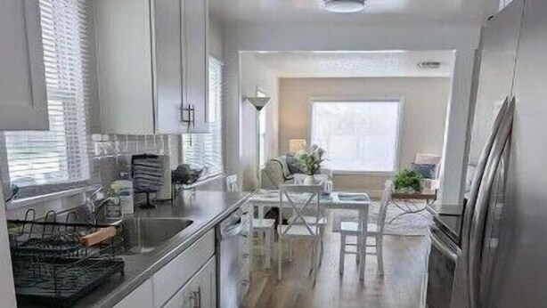 A modern kitchen with white cabinetry, a central island, and a dining area with a table and chairs. - Quaint Murray Home- 2 bed/1 bath  20 min to ski/hike or downtown. 5 min to IMC. (Murray)