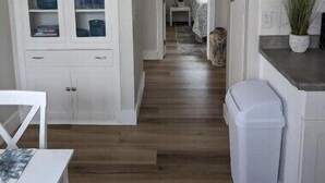 A kitchen with white cabinets, a wooden floor, and a view into the dining area. - Quaint Murray Home- 2 bed/1 bath  20 min to ski/hike or downtown. 5 min to IMC. (Murray)