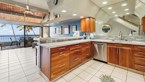 A modern kitchen with wooden cabinets, a dishwasher, and a large island.
