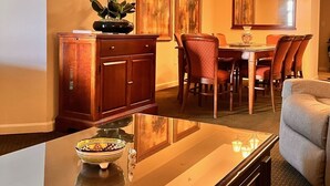 Un comedor con una mesa y sillas de madera, una araña y un jarrón con flores.