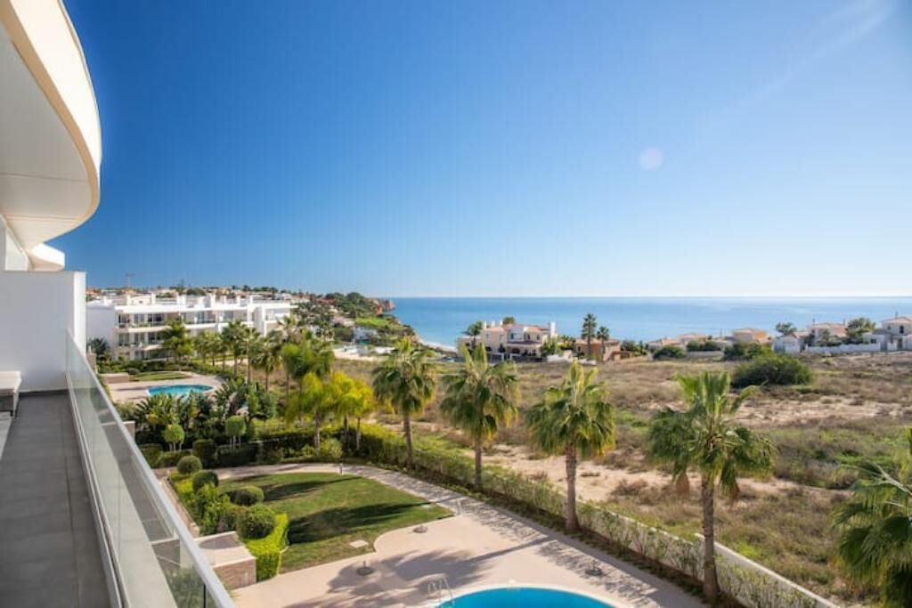 Ein Balkon mit Blick auf einen Pool, Palmen und eine Küstenlandschaft.