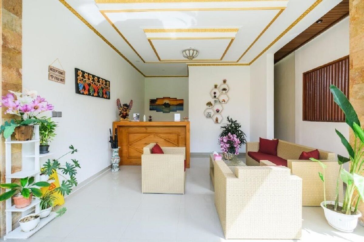A modern living room with a wooden reception desk, wicker furniture, and potted plants.
