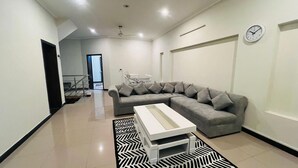 Ein modernes Wohnzimmer mit einem grauen Ecksofa, einem weißen Couchtisch und einem gemusterten Teppich.
