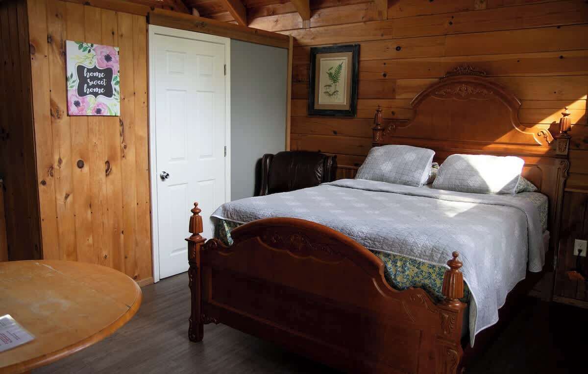 A wooden room with a bed, a chair, and a table.