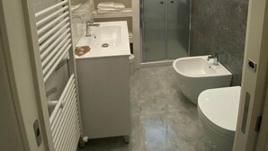 Une salle de bain moderne avec une douche à l’italienne, un meuble-lavabo double et des toilettes.