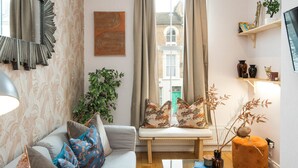 A cozy living room with a sofa, a bench, a coffee table, and a bookshelf. - Charming 1-bed Apartment in London (London)
