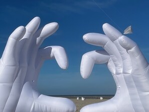 Una playa con grandes estructuras hinchables blancas que parecen manos.